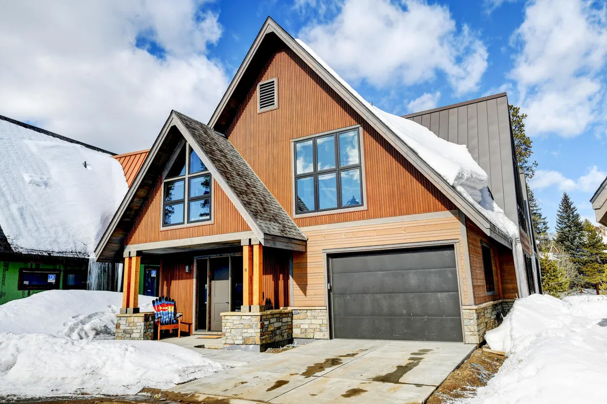This exterior shot showcases the chalet's A-frame architecture with large windows, a wooden and stone facade, and a snow-covered ground, hinting at the private yet inviting mountain retreat vibe. The scene implies space for family gatherings and outdoor relaxation in a picturesque winter environment.