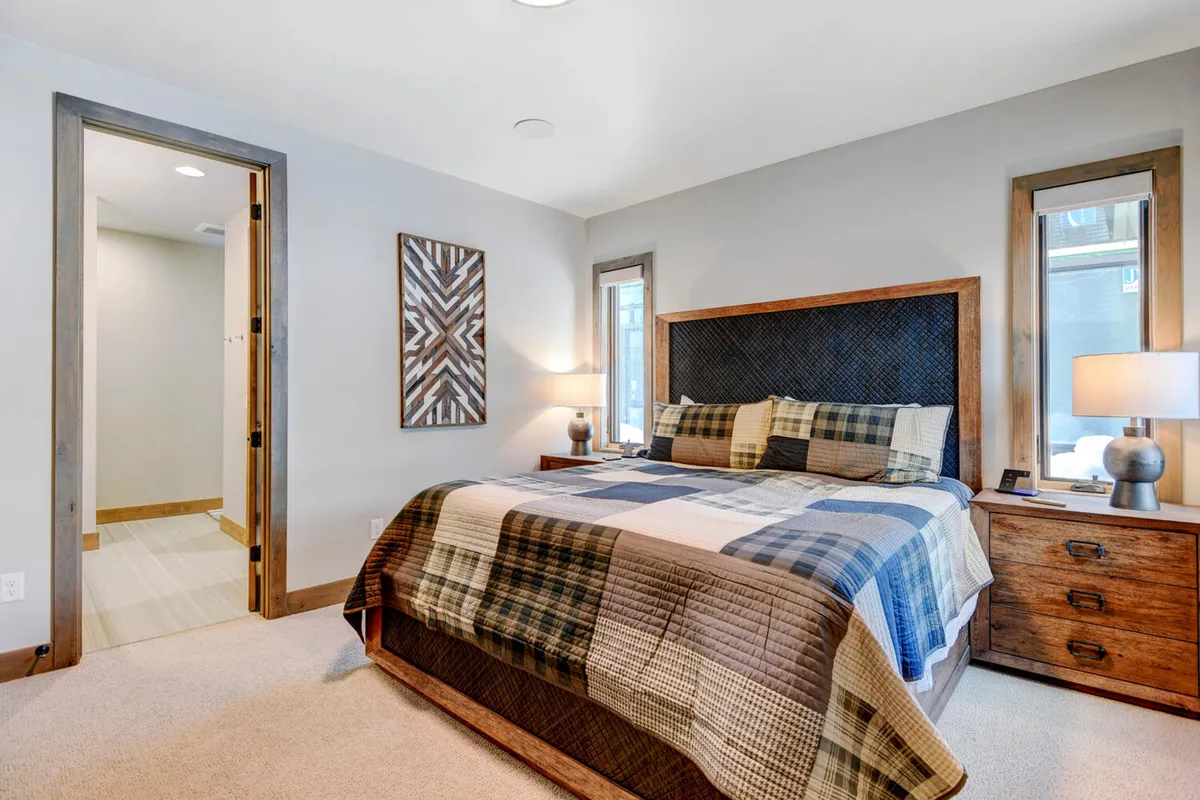 A king bedroom with an inviting bed, plush quilt, nightstand with a lamp, and tasteful wall art creates a restful atmosphere. The soft lighting and cozy textures highlight the comfort and premium bedding mentioned in the section.