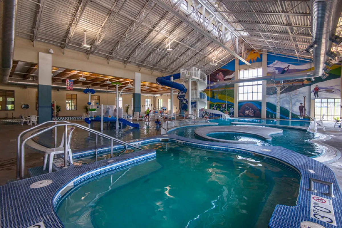 A vivid indoor scene at a recreation center, showcasing colorful water slides and a swimming pool where kids and families are having a blast.