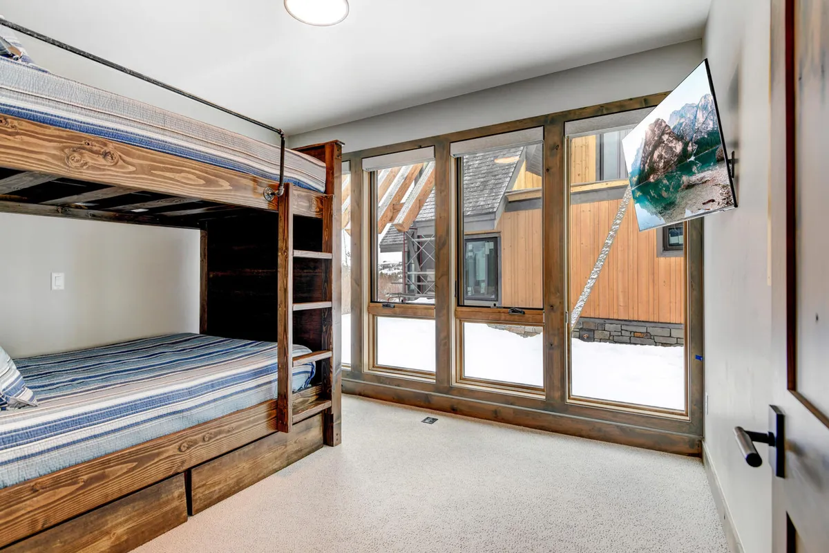 A full bunk room with multiple bunk beds, large windows, and a television. The space is designed for both fun and comfort, making it ideal for families with children or groups of friends.